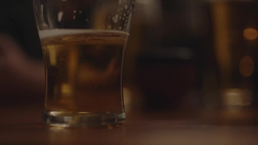 Close up view of a person lifting a glass of beer