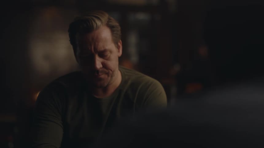 A man is sitting in a bar and drinking a beer