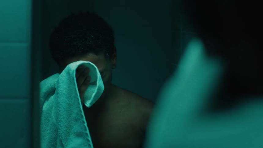 Shirtless young man drying himself with a towel in front of a mirror