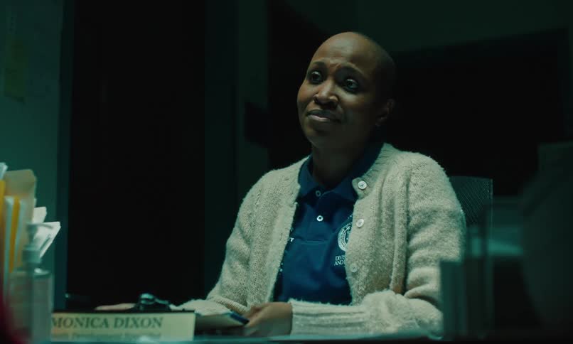 Woman finishes discussion with a slight smile then sighs and leaves desk decorated with her name plate