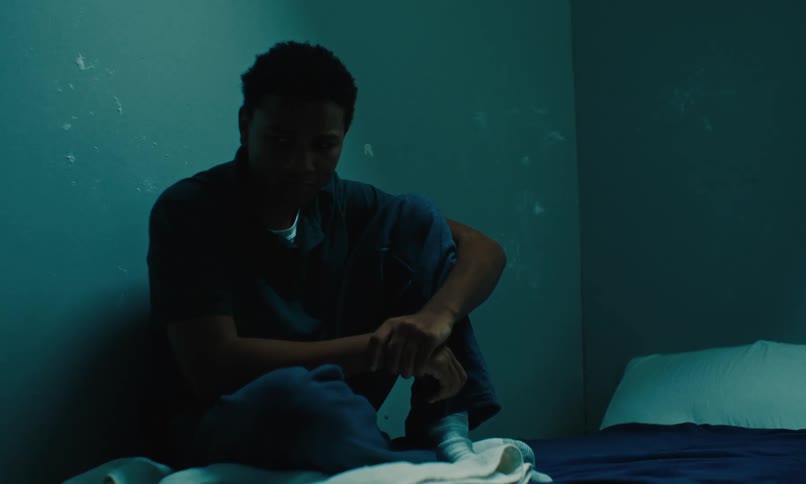 A sad inmate sitting on the cell bed