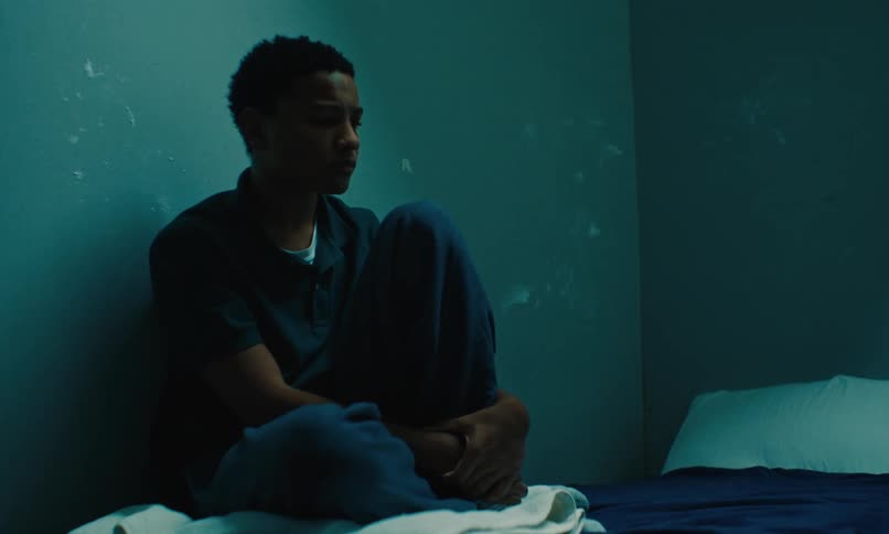 A teenager sits against the wall in bed