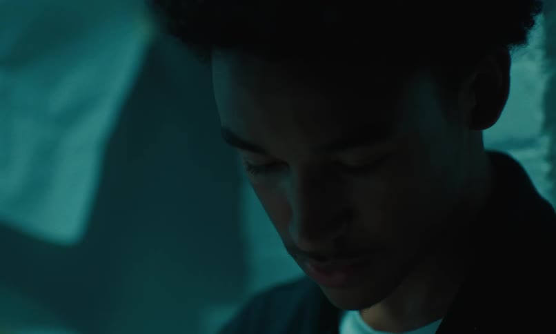 Close up of a teen boys face looking down toward his feet while thinking