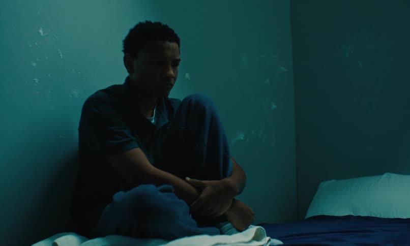 Sad young man sitting on the prison cell bed alone