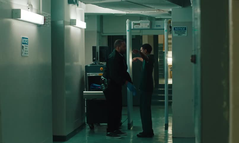 A prisoner passing through the metal detector and being frisked by the prison guard