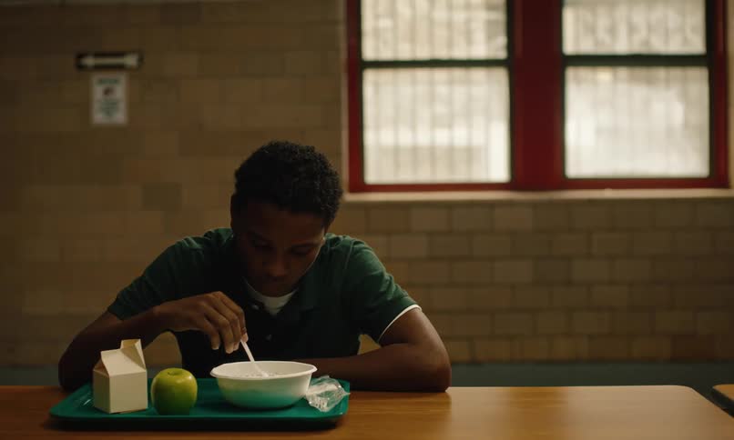 The view is of a portrait of a boy that is eating lunch at school