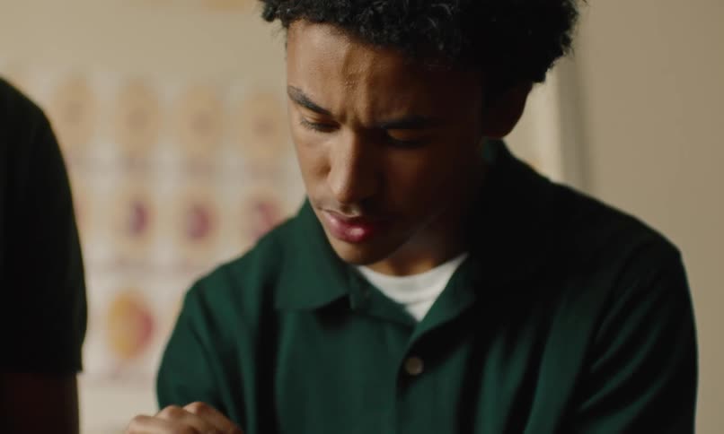 Baby chick being handed off to a teenage boy who holds it up and looks at it contemplatively