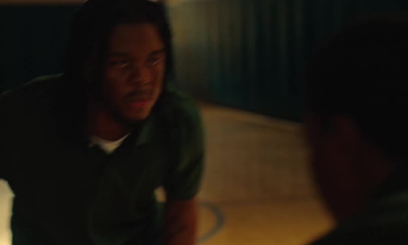 A man dribbles a basketball as he walks towards another man as they play basketball together