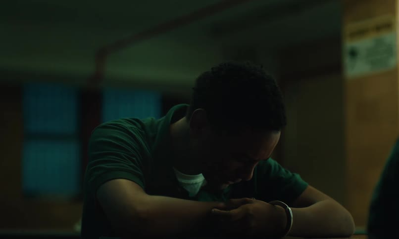 Young inmate handcuffed and visibly upset sitting at a table and starting to cry