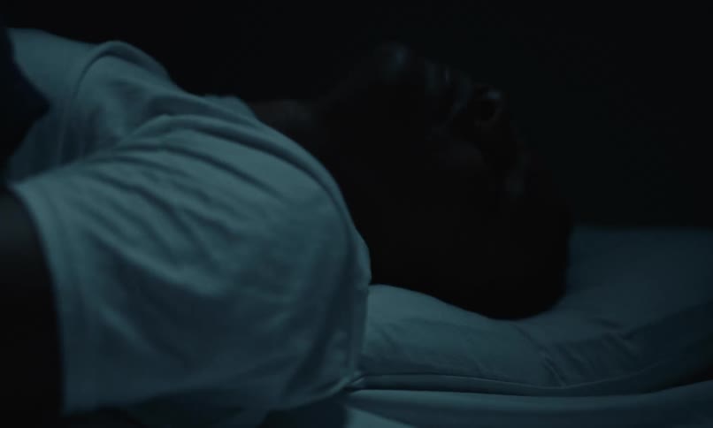 A close up of a person rolling around in their bed as they toss side to side and curl over