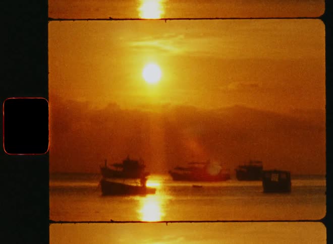 Boats and ferry boats sail off the coast while the sun shines brightly
