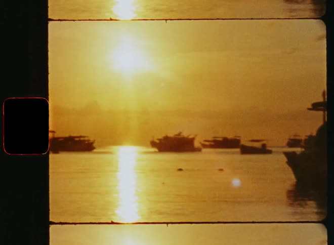 The silhouette of ships docked in a harbor as the sun sets over the water