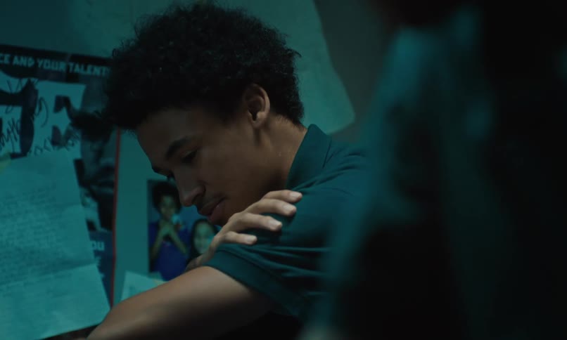 Two teenage boys sitting near each other as they converse and look upset