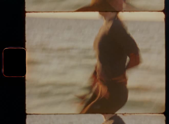 Dynamic handheld 8mm film of female personal coach on a pier in the ocean running in place with high knees and fast steps wearing workout clothes and doing exhausting sport exercises according to her outdoor fitness app