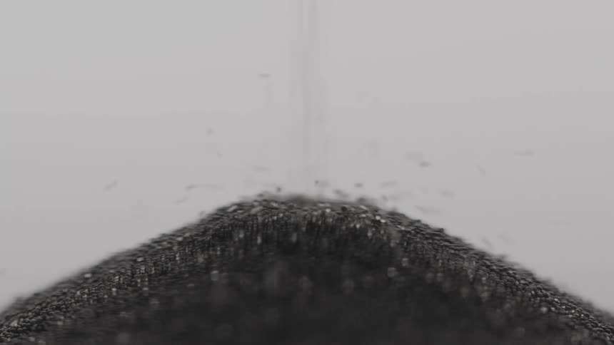 Dark grainlike particles fall into a pile