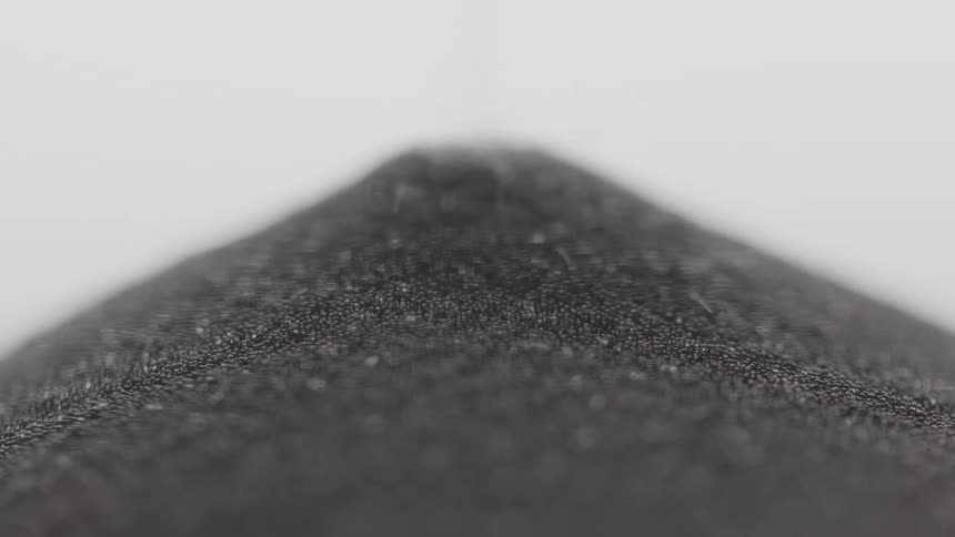 A close up of black sand oouring through an hourglass