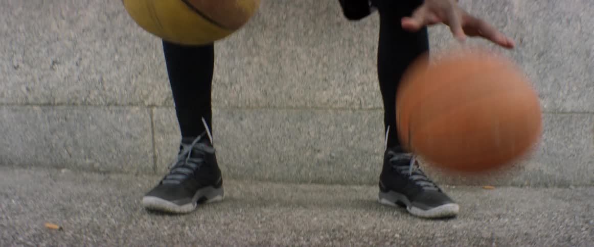 A man is dribbling two basketballs at once