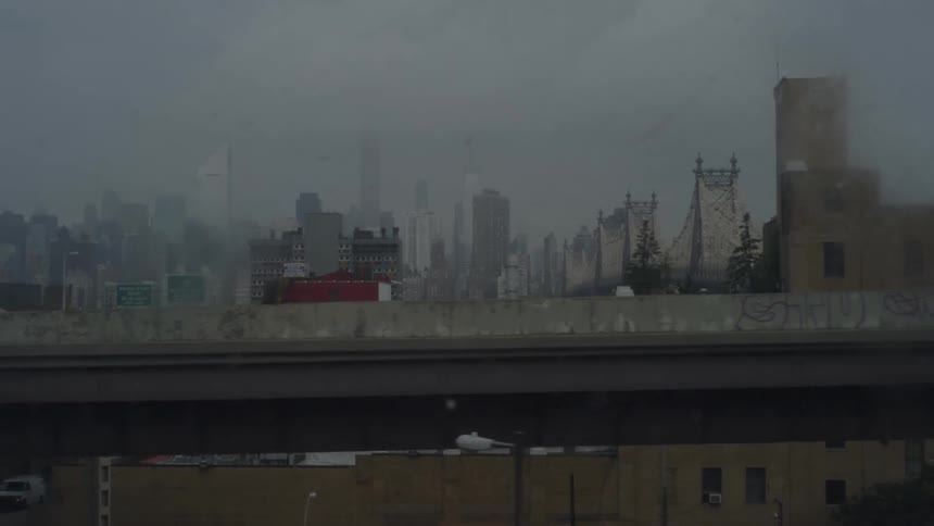 A view of a city skyline along a bridge on a hazy rainy overcast day