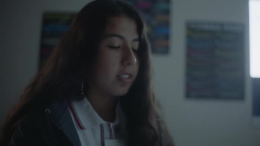 A teenager reading a book and attentively listening in the classroom