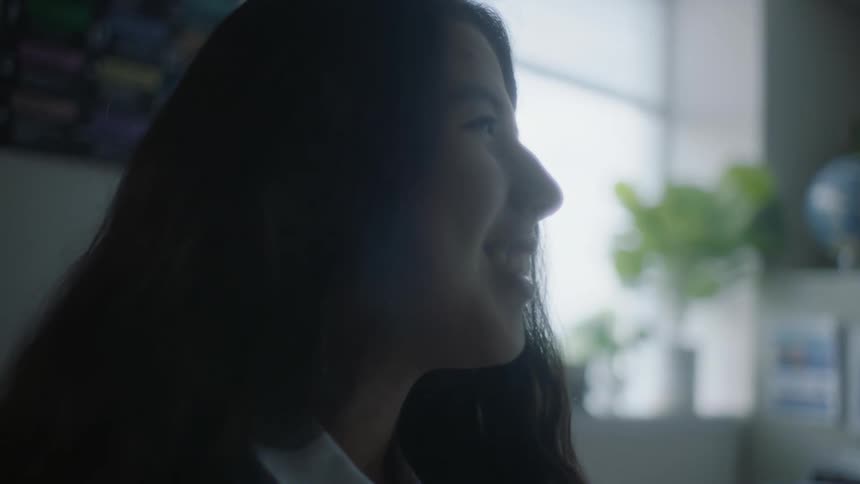 A womans face close up as she smiles laughs and talks to someone in front of her