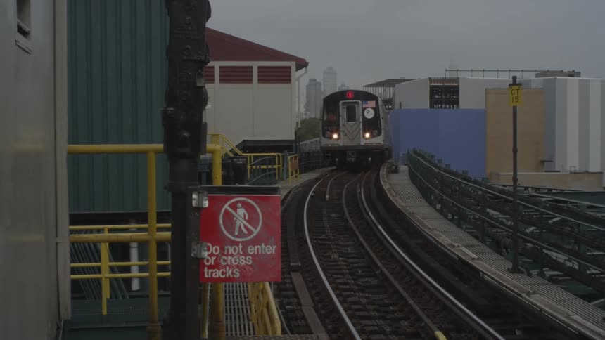 Train pulls up to a station stop that has a red caution sign