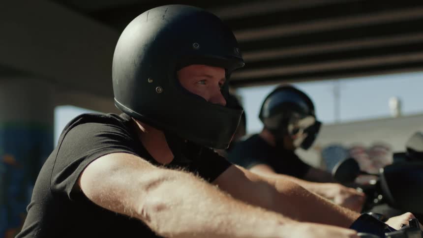 A man sits on a motorcycle next to two other people on a motorcycle as he prepares to drive
