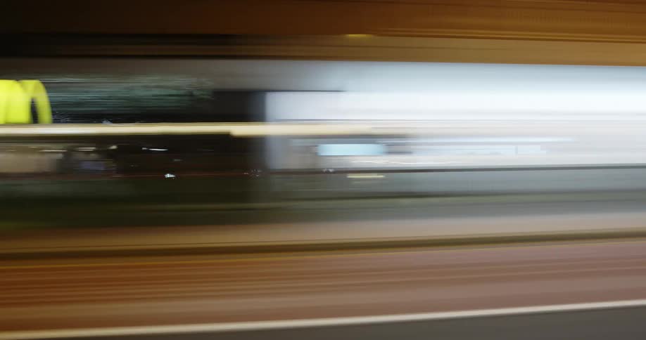 A time lapse of a city street with neon lights lighting up the street signs as they blur past the frame