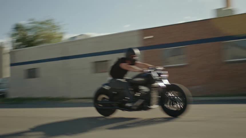 A pair of bikers ride motorcycles down a wide road during the day