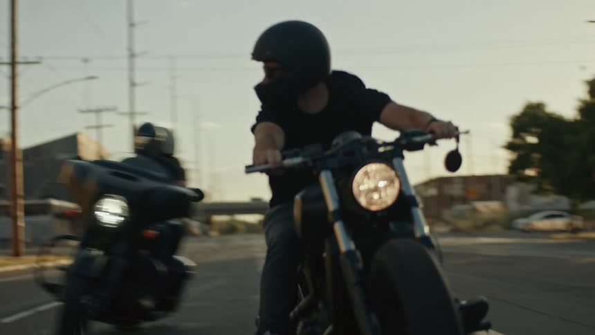 Two men riding motorcycles down the road weaving in and out of each other