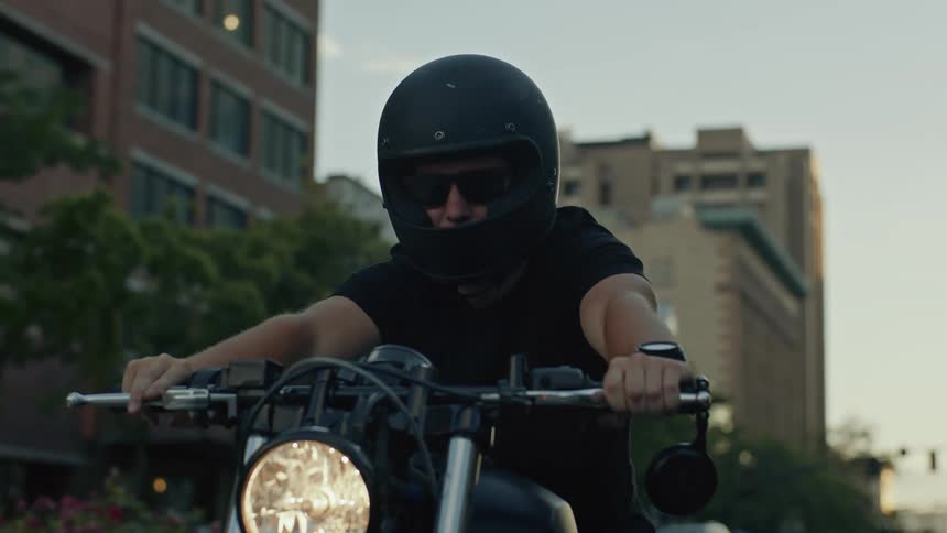 A man pulls up on a motorcycle in the city
