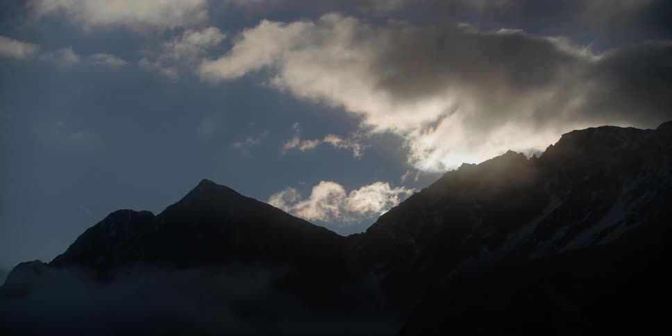 A shadowy mountain ridge beneath the daytime sky