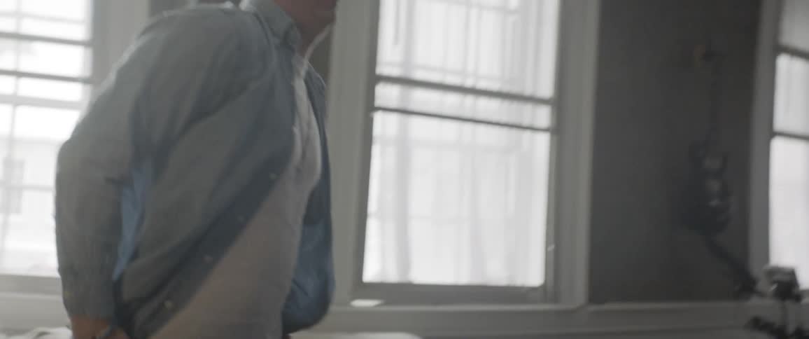 Man looks at his phone and gets up from the couch to walk away