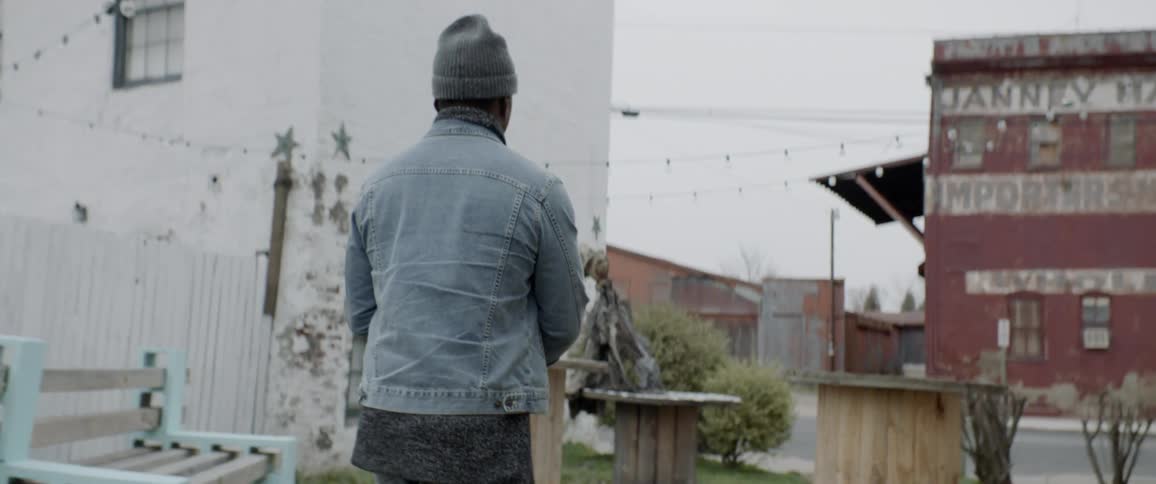 A man wearing a hat is walking outside in the city
