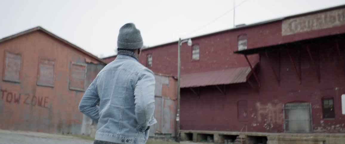 Man walks toward an old warehouse during the winter