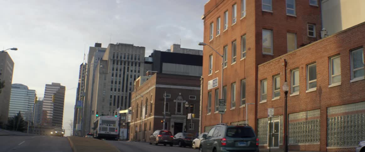 Cars drive down a city street on a cloudy day