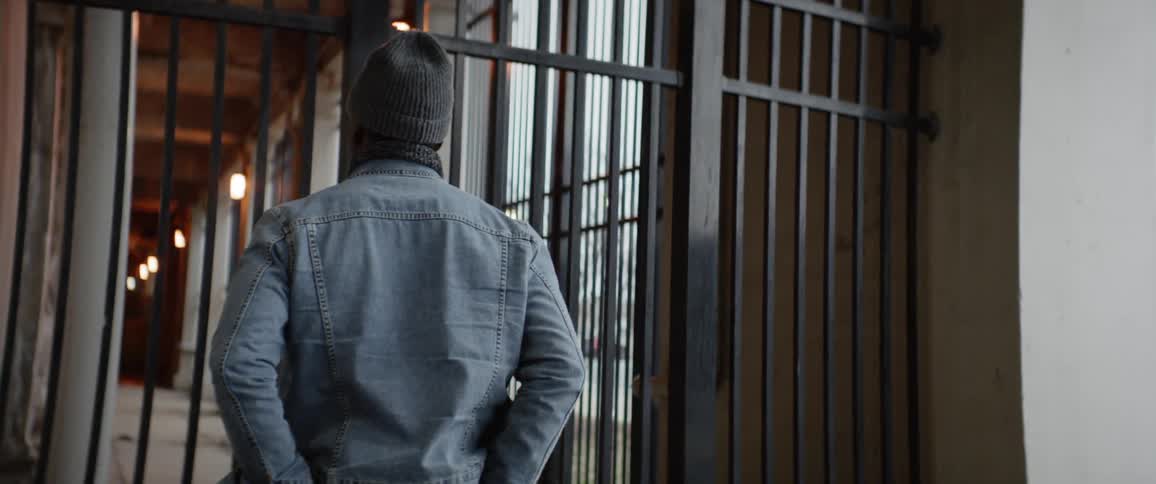 A man stands in front of an iron bar fence