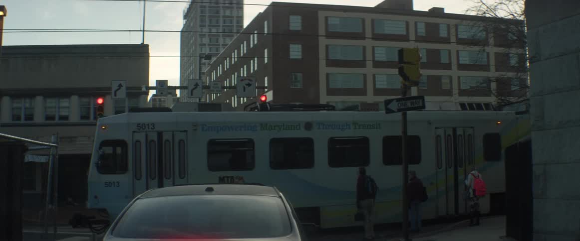A car and people are stopped waiting for a train to pass