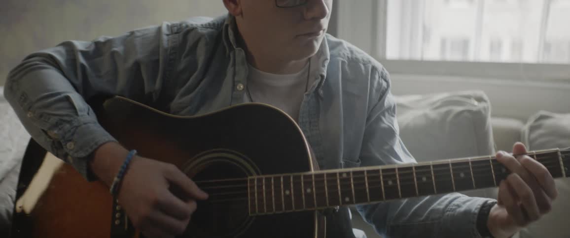 A man sitting on a sofa playing the guitar