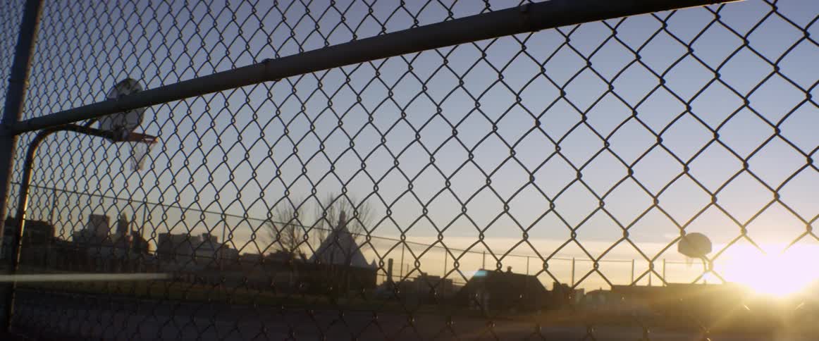 Behind the fence is an empty basketball court