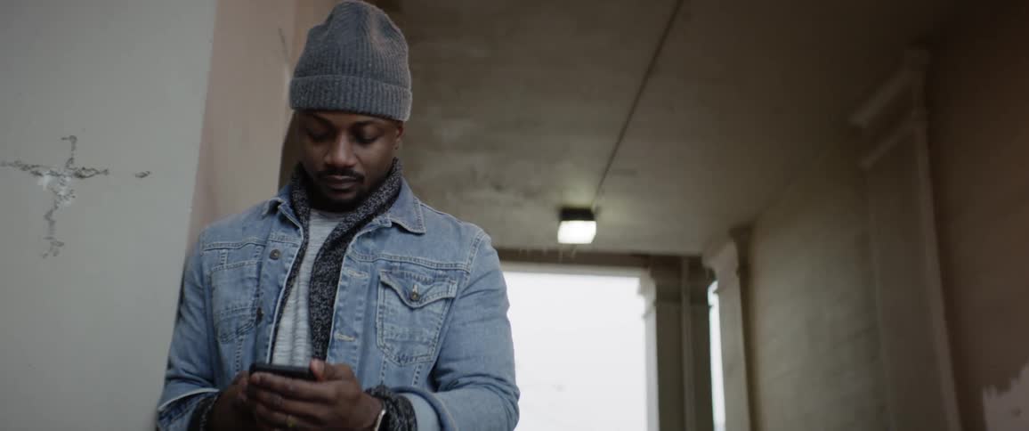 A man looks at a phone in the entryway of a building