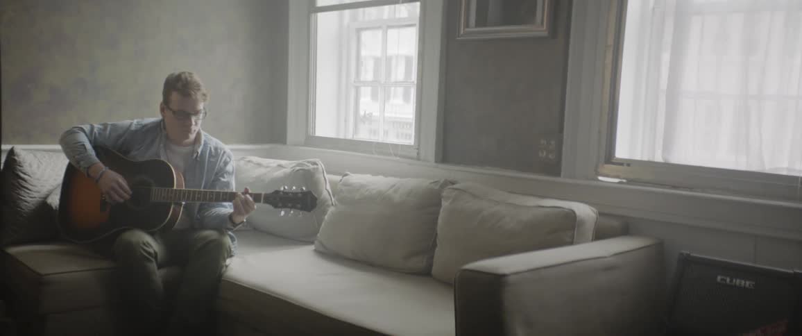 A man playing a guitar on a sofa