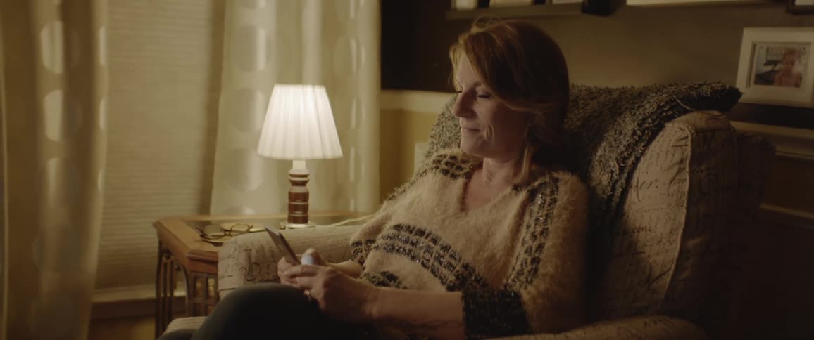 Woman sits in a chair as she scrolls on her cellphone