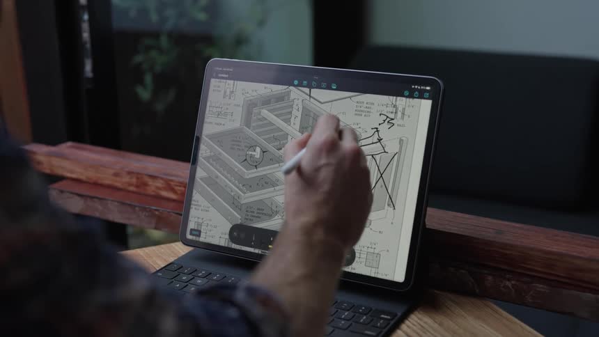 Close up of a man writing with a pen on a tablet screen to draw plans