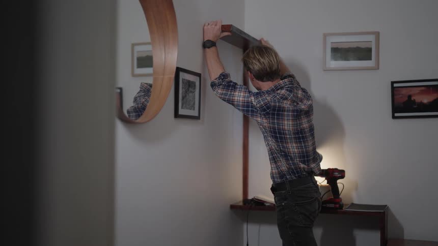 The view is of a portrait of a man that is putting up a shelf