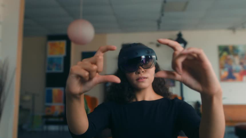 Woman wearing a pair of electronic goggles interacting with what she sees using her hands