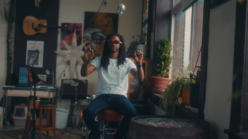 Man sitting on a stool in a room wearing a pair of vr glasses and moving his hands around in the air