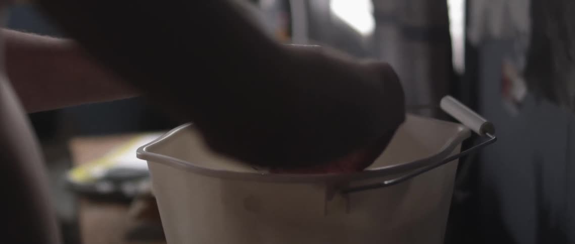 A person squeezes a washcloth from a bucket of water
