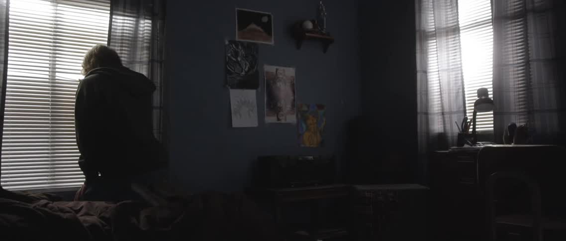 Teenager looking through the window on his bedroom in the middle of the day