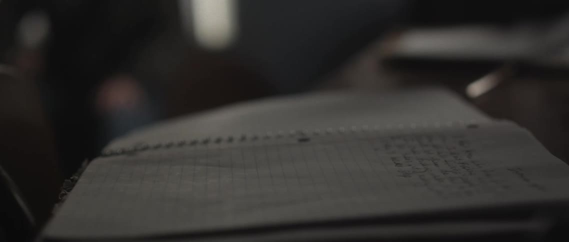 Person walks to table and picks up open notebook