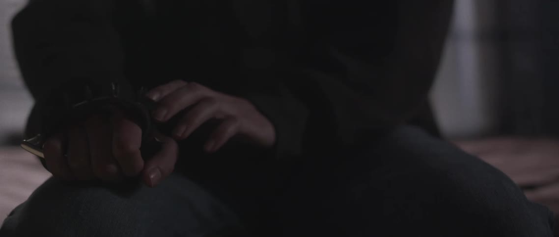 A person is sitting in bed touching their hand